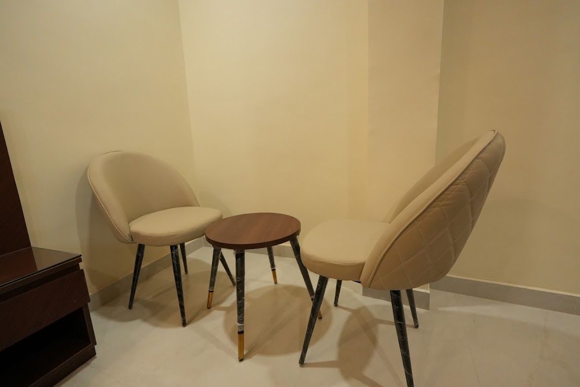 A room with two beige chairs and a small round table.