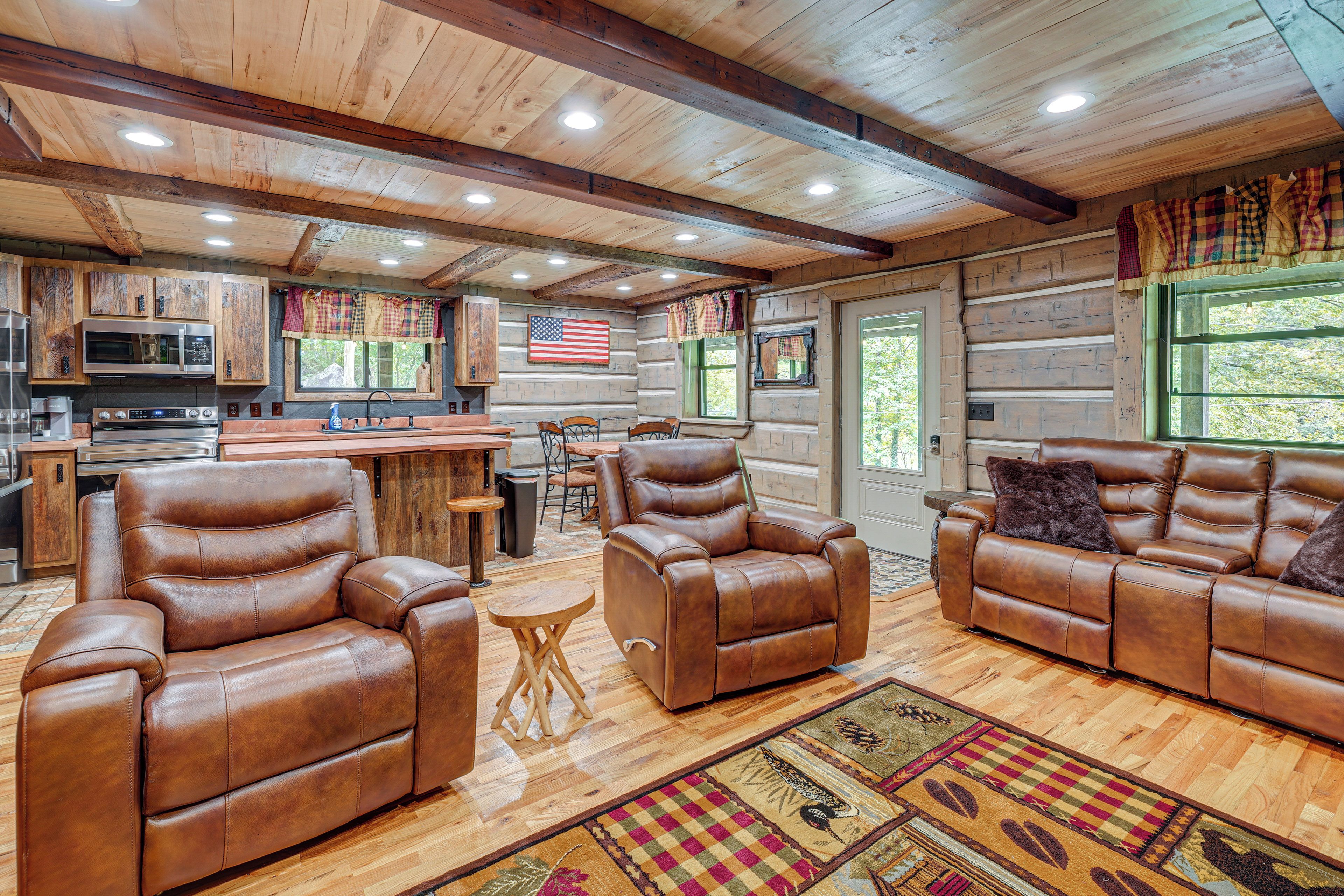 A spacious living area with leather sofas, a wooden ceiling, and a kitchen with modern appliances.