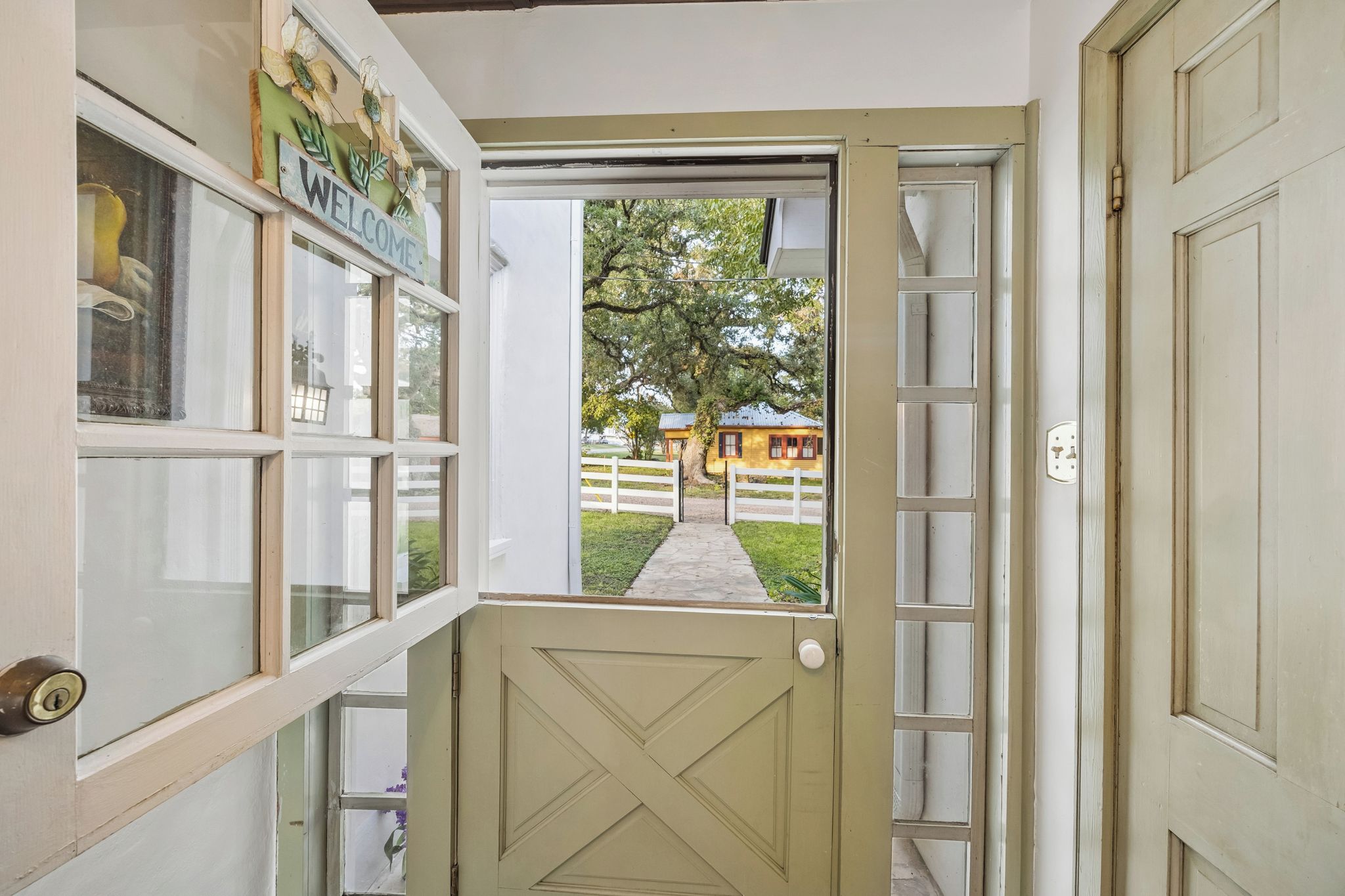 A doorway leading to a property with a white door and a window with a 'WELCOME' sign.
