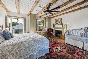A bedroom with a large bed, a sofa, a fireplace, and a ceiling fan. - Pond & Longhorn Views! Timeless Round Top Retreat (Round Top)