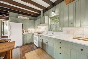 Una cocina con gabinetes verde claro, un refrigerador blanco, una estufa y un microondas.