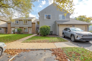 A two-story residential building with a garage, a driveway, and a parked SUV. - Convenient Condo 9 Mi to Princeton University (Hightstown)