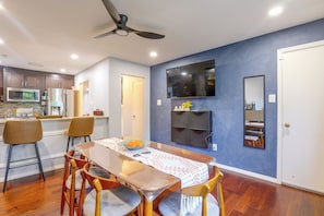 A modern kitchen with a dining area, a ceiling fan, and a flat-screen TV mounted on the wall. - Convenient Condo 9 Mi to Princeton University (Hightstown)