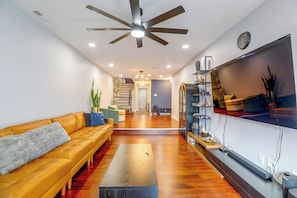A modern living room with a sofa, coffee table, and a TV mounted on the wall. - Convenient Condo 9 Mi to Princeton University (Hightstown)