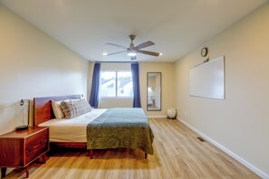 A bedroom with a bed, a bedside table, a ceiling fan, a window with curtains, a mirror, and a whiteboard on the wall. - Convenient Condo 9 Mi to Princeton University (Hightstown)