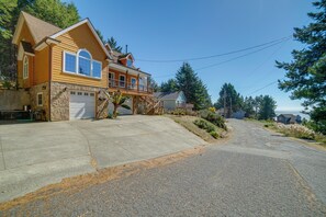 A residential street with two houses, one with a garage and a balcony, and the other with a porch.