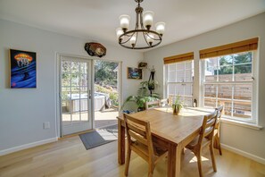 A dining area with a wooden table and chairs, a chandelier, and a view of a hot tub outside. - Retreat 1 Mi to Black Sands Beach & Trails! (Shelter Cove)
