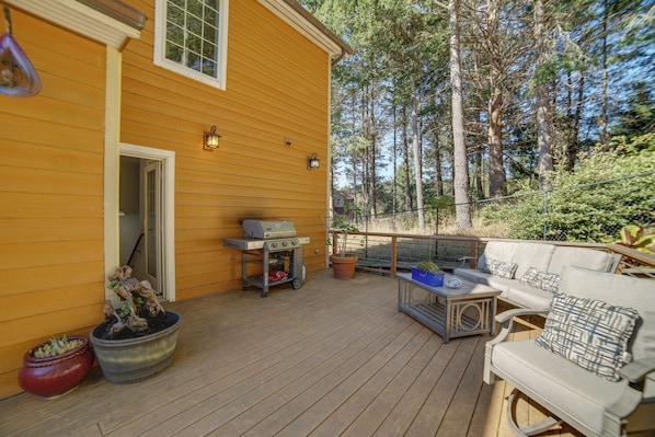A wooden deck with a grill, outdoor seating, and potted plants.