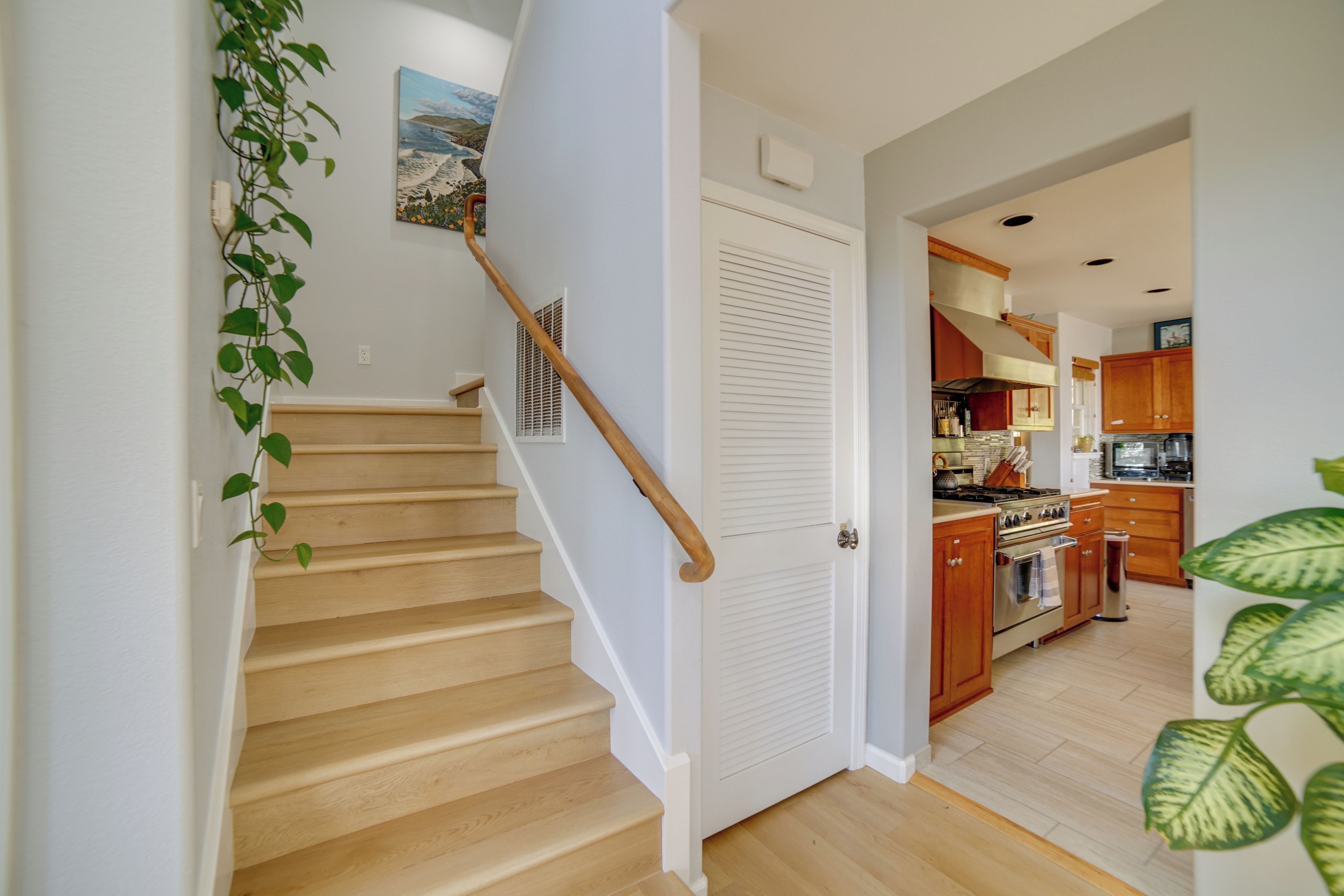A staircase with wooden steps and a handrail, leading to a room with a white door and a vent.