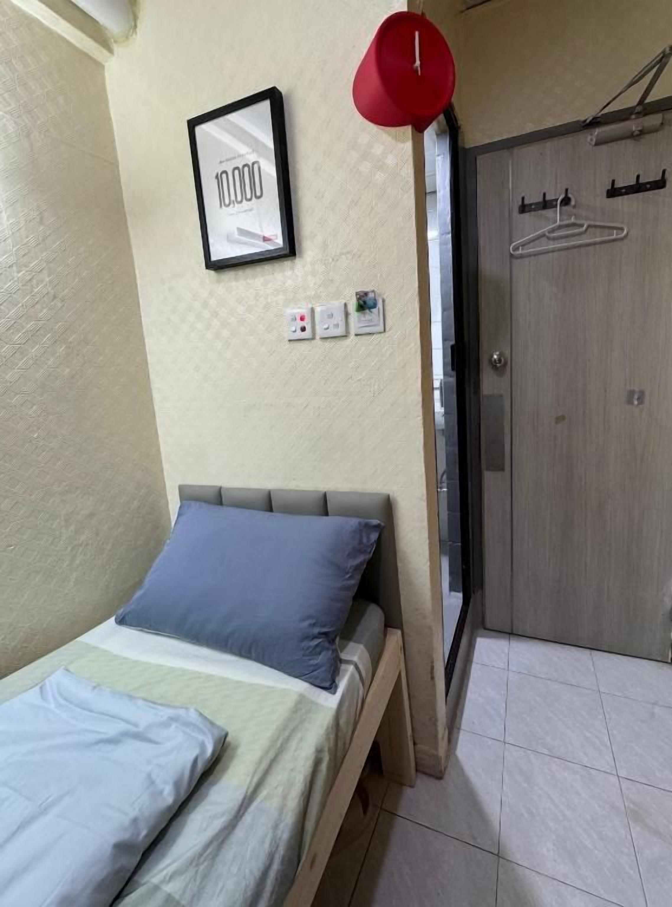 A bedroom with a bed, a red hanging light, a framed picture, and a wardrobe.