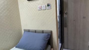 A bedroom with a bed, a red hanging light, a framed picture, and a wardrobe.