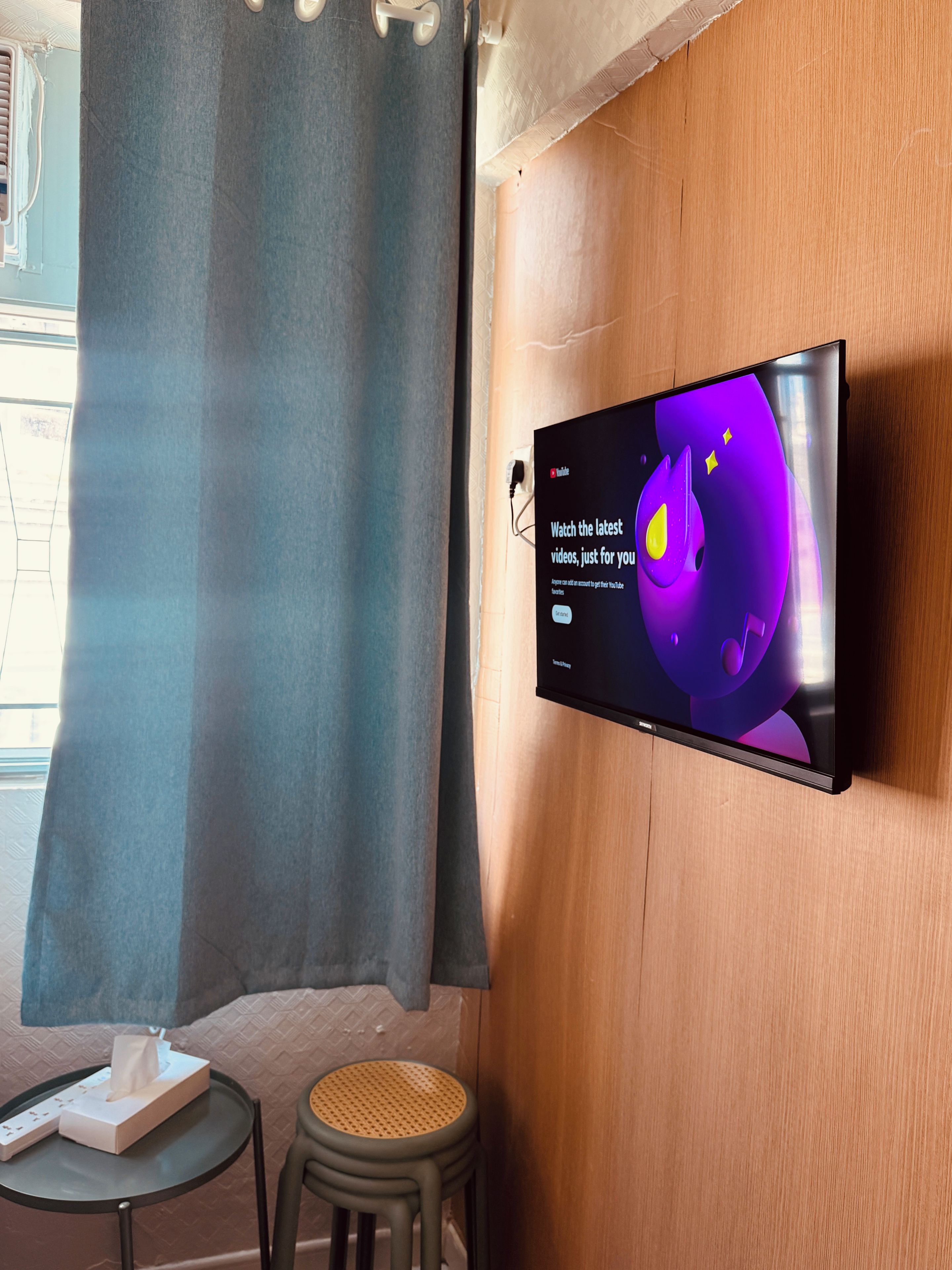 A flat-screen TV mounted on a wooden wall displaying a YouTube interface.