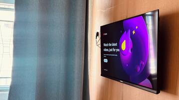 A flat-screen TV mounted on a wooden wall displaying a YouTube interface.