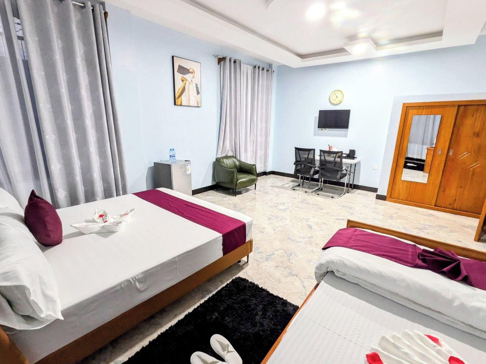 Une chambre d’hôtel avec deux lits, un bureau, une chaise, une télévision et une armoire.