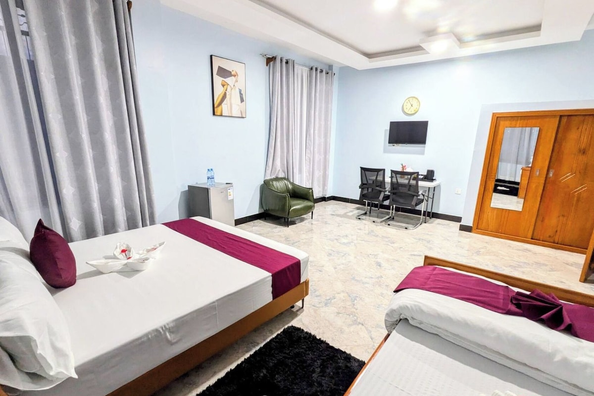 Ein Hotelzimmer mit zwei Betten, einem Schreibtisch, einem Stuhl, einem Fernseher und einem Kleiderschrank.