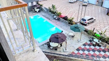 Un área de piscina en la azotea con piso a cuadros, mobiliario exterior y vista al estacionamiento.