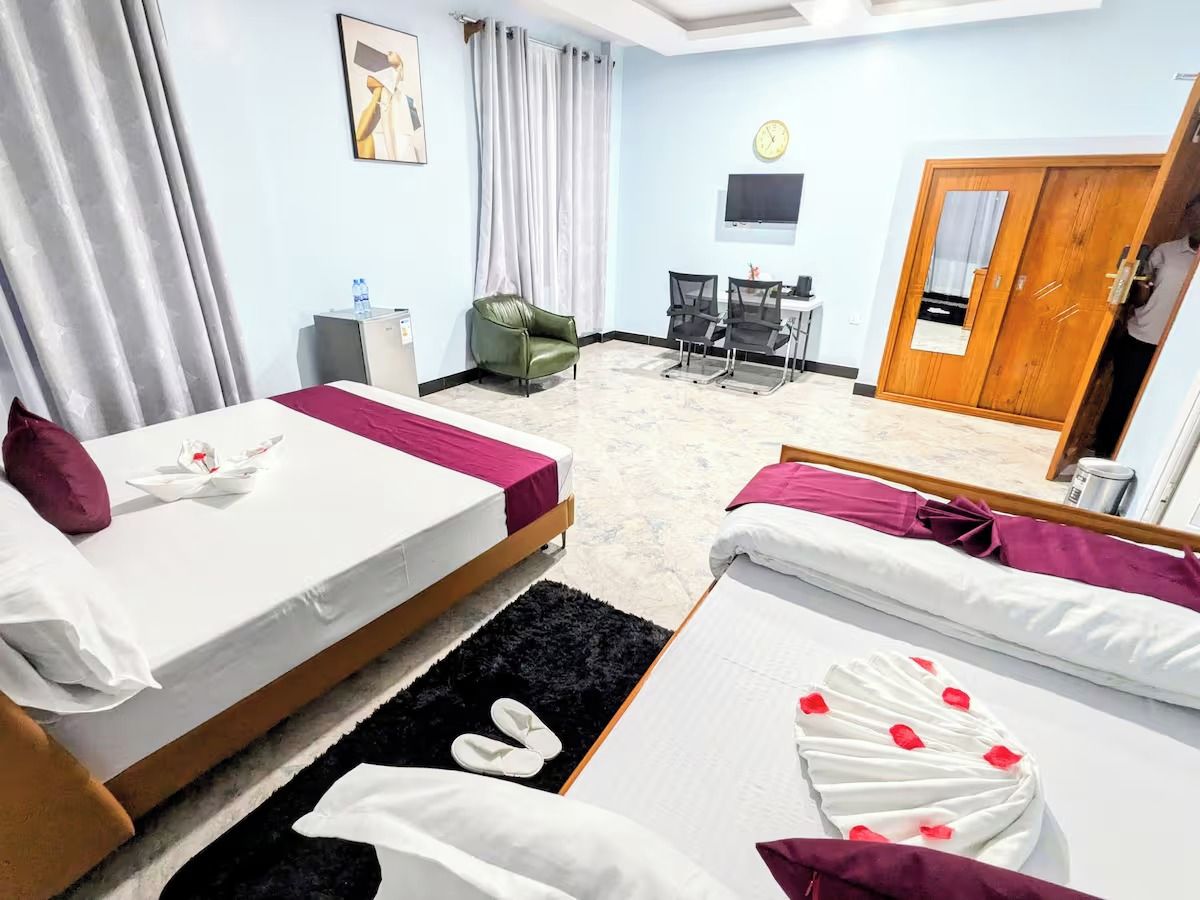 Une chambre d’hôtel avec deux lits, un bureau, une chaise, une télévision et une porte.