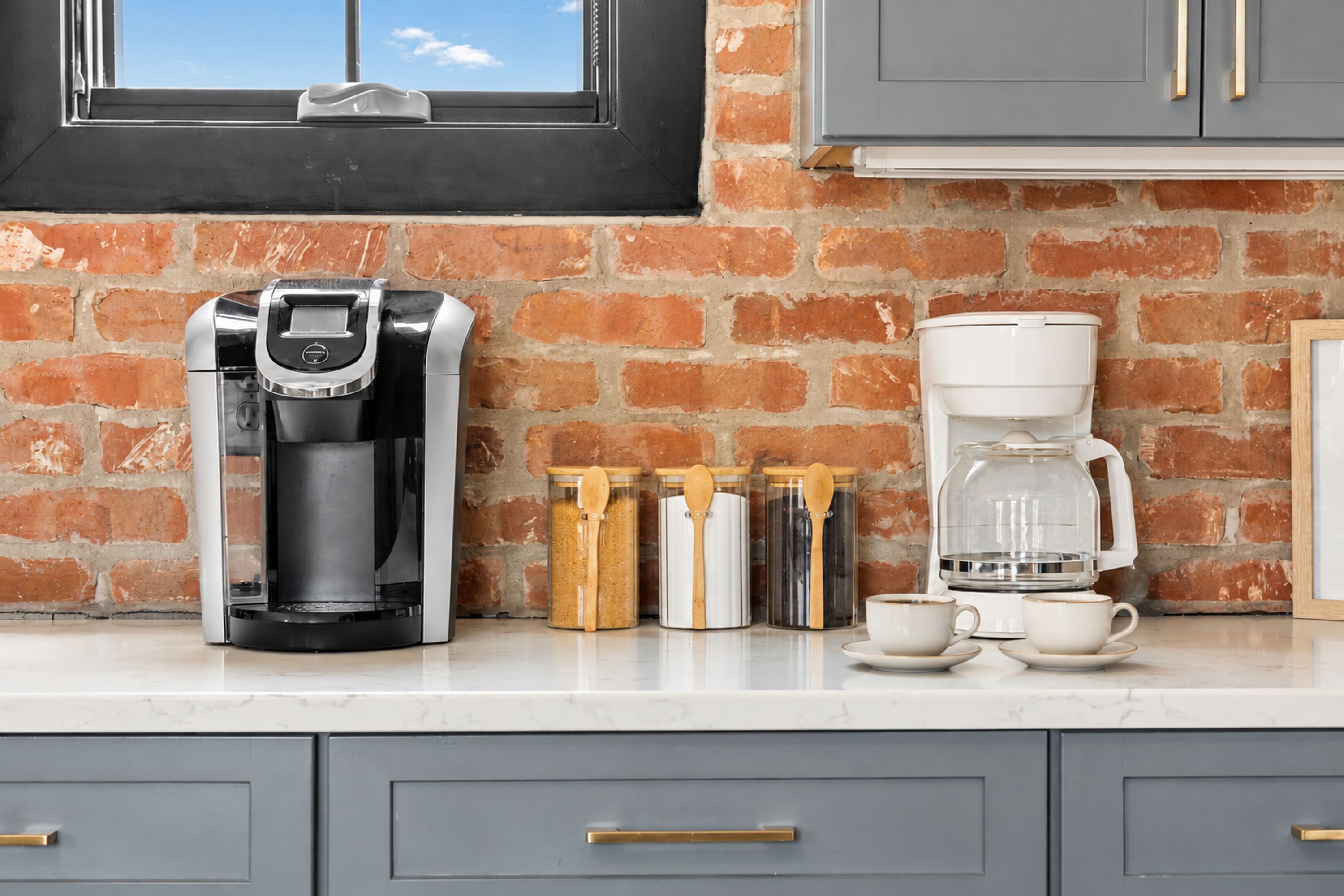 A kitchen with a coffee maker, a glass carafe, and a coffee pot on the counter.