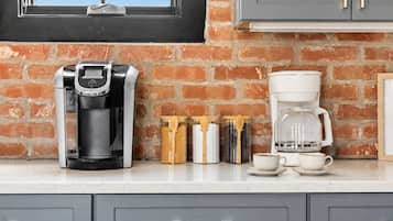 A kitchen with a coffee maker, a glass carafe, and a coffee pot on the counter.