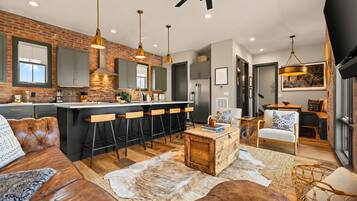A modern kitchen with a brick wall, bar stools, and pendant lighting.