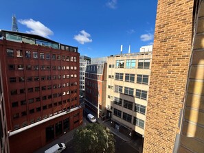 A multi-story building with a brick facade and large windows, featuring a central courtyard with a tree. - City Double VII - Stylish 2BR Home in the City (London)