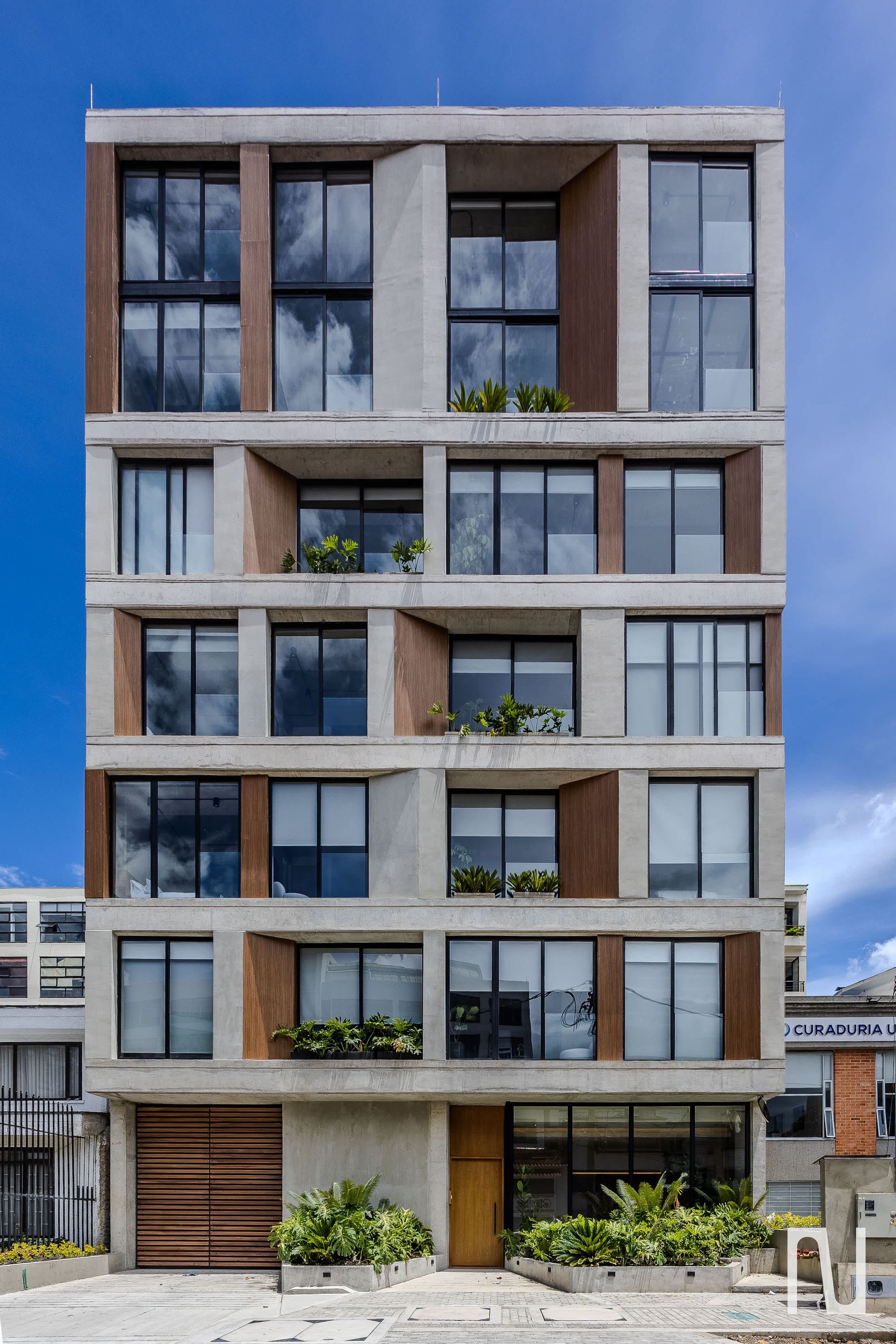 A multi-story building with a flat facade, large windows, and a central entrance with a wooden door.
