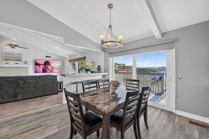 A modern kitchen with a large island, a dining area with a marble table, and a balcony with a scenic view. - Lagoonfront 3BR Pickleball Kayaks Basketball (Carlsbad)