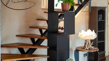 A staircase with wooden steps and black metal supports, a potted plant on the landing, and a small table with a decorative item.