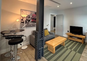 A modern living room with a sofa, a coffee table, a TV stand, and a bar stool. - City Tower - Stylish 1BR Home in the City (London)