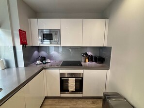 Een kleine keuken met een magnetron, koffiezetapparaat, broodrooster en oven.