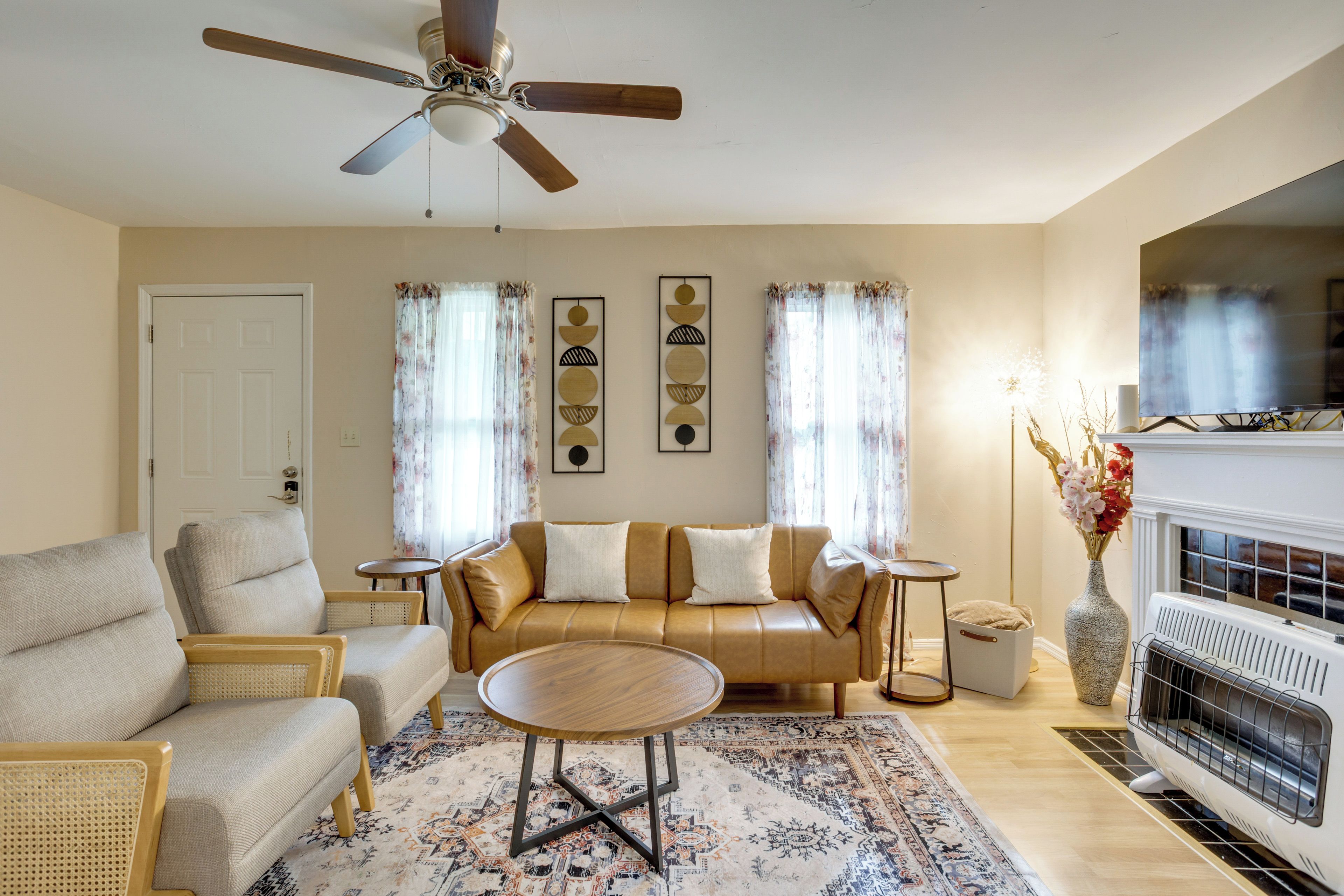 A living room with a sofa, chairs, a coffee table, a fireplace, and a ceiling fan.