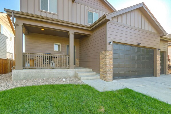 A two-story house with a covered front porch, a garage, and a stone accent wall.