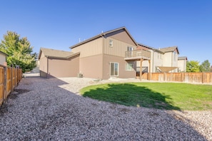 A two-story house with a gravel driveway and a fenced backyard.
