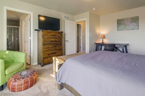 A bedroom with a bed, a wooden dresser, a green armchair, a small table with a lamp, and a painting on the wall. - Family-friendly Home! Walk to Windsor Lake (Windsor)