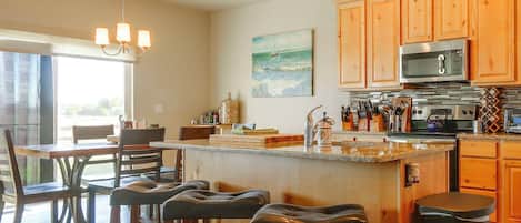 A modern kitchen with wooden cabinets, a stainless steel oven, and a bar area with stools.