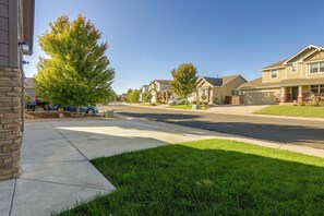 A residential street with houses, a clear sky, and a well-maintained lawn.