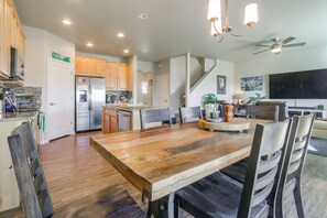 Una cocina moderna con horno integrado, refrigerador y comedor con mesa y sillas de madera.