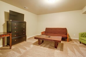 A living room with a brown sofa, a wooden coffee table, a TV on a dresser, and a green armchair.