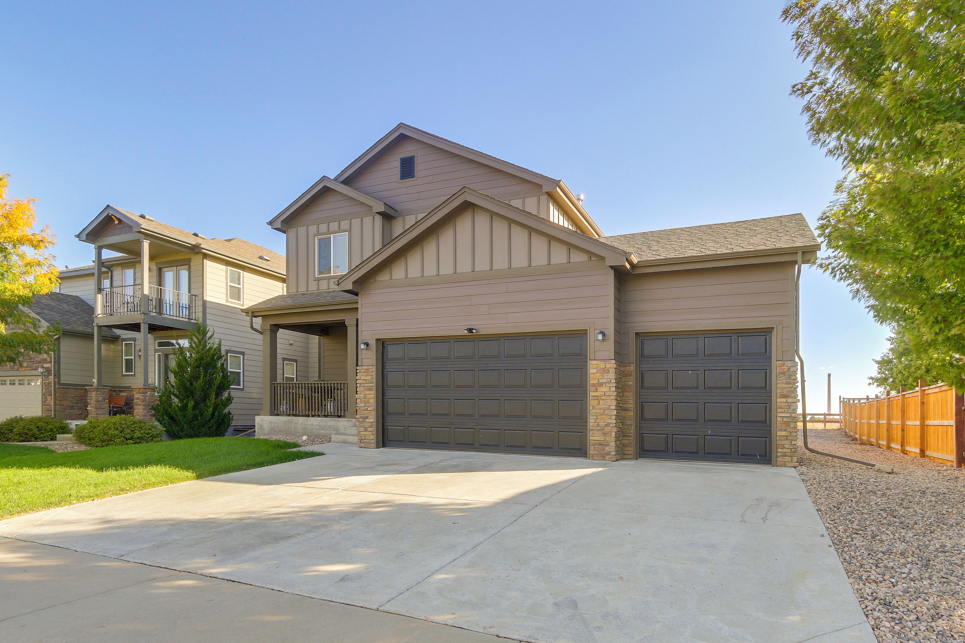 A two-story house with a garage, a covered porch, and a landscaped front yard.