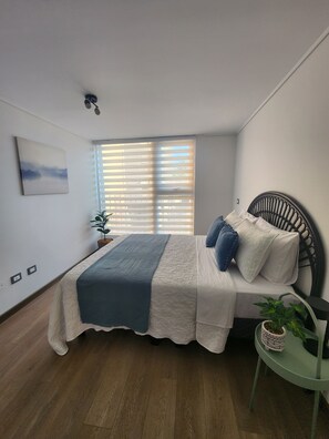 A bedroom with a bed, a window with blinds, a wall-mounted light fixture, and a small table with a plant. - Marvelous 2-bedroom apartment in peaceful Ñuñoa neighborhood (Ñuñoa)