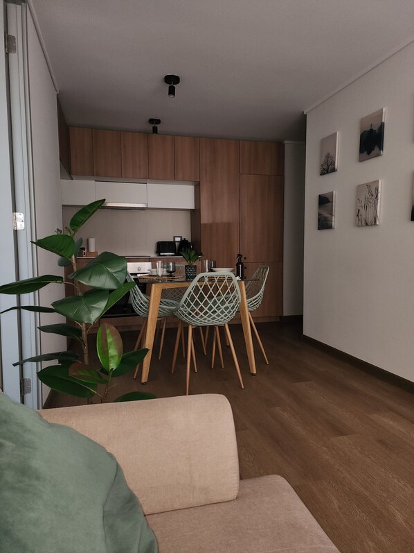 A modern kitchen with wooden cabinets, a dining table with chairs, and a living area with a sofa. - Marvelous 2-bedroom apartment in peaceful Ñuñoa neighborhood (Ñuñoa)
