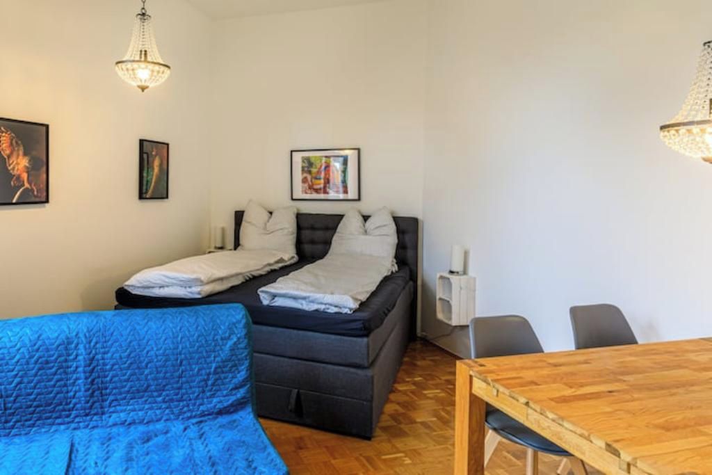 Ein Zimmer mit einem Bett, einem blauen Sofa, einem Holztisch und zwei Pendelleuchten.