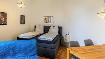 Ein Zimmer mit einem Bett, einem blauen Sofa, einem Holztisch und zwei Pendelleuchten.