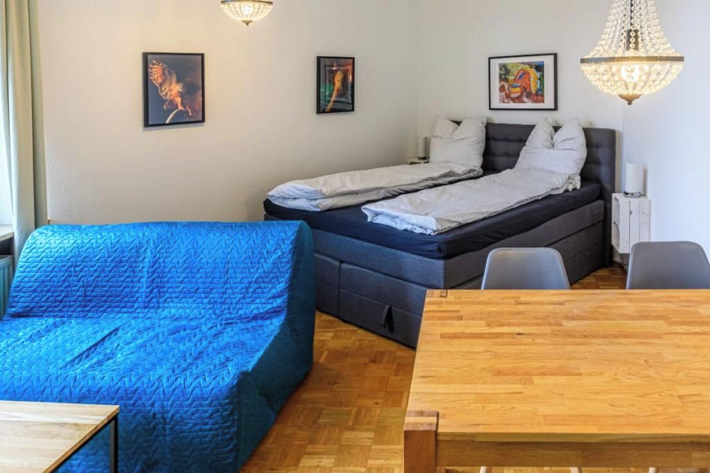 Een kamer met een bed, een slaapbank, een eettafel en kunstwerken aan de wanden.