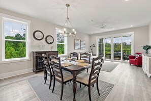 A spacious dining area with a large table, chairs, and a chandelier. - Moorings 101 – Marshview Sanctuary | 3BR/3BA • Pool • Screened Porch (Jekyll Island)