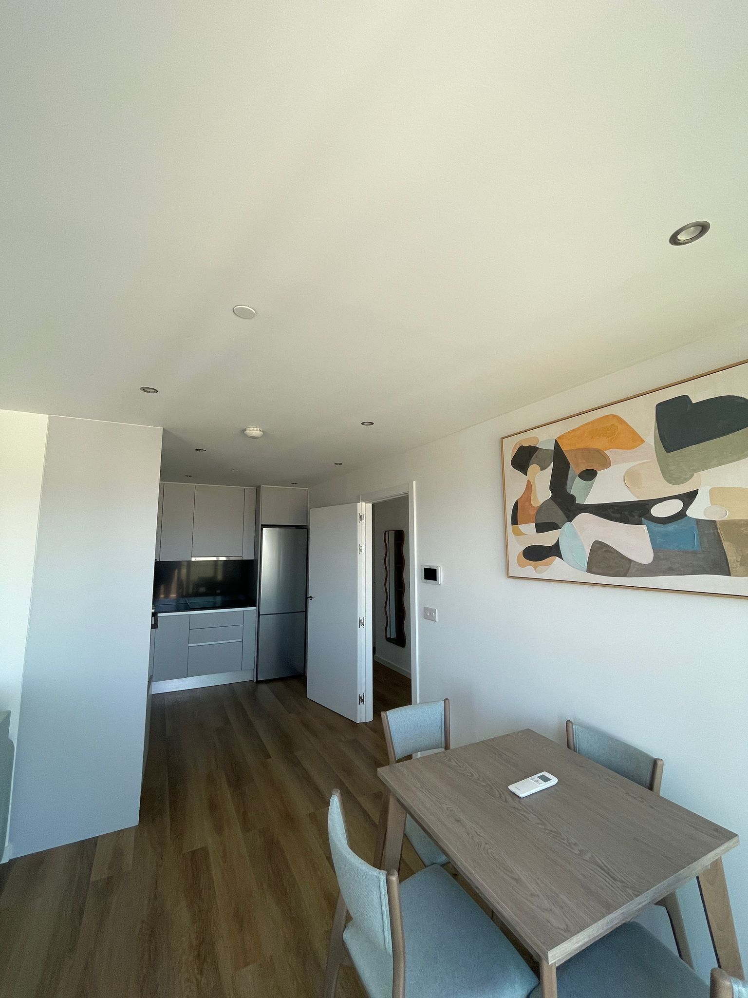 Una cocina moderna con armarios blancos y un refrigerador de acero inoxidable.
