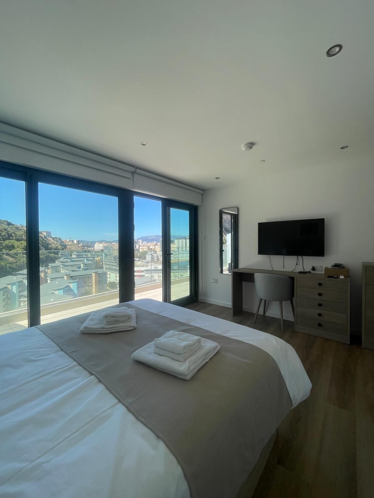 Una habitación de hotel moderna con una cama grande, un escritorio, una silla y un televisor.