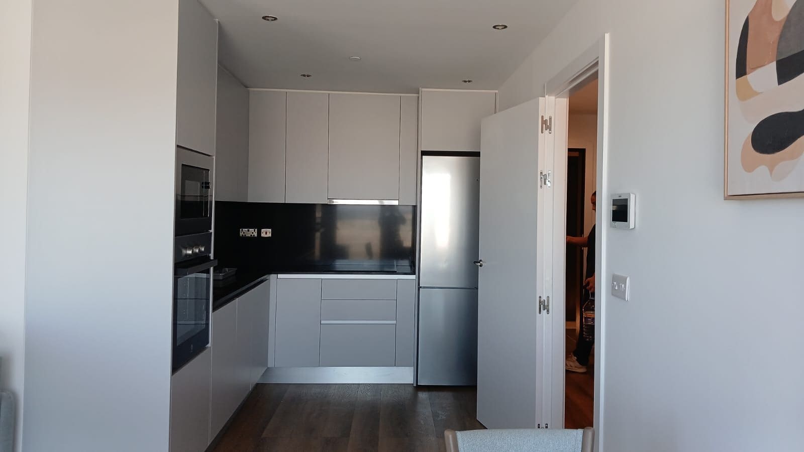 Una cocina moderna con armarios blancos, encimera negra y electrodomésticos de acero inoxidable.