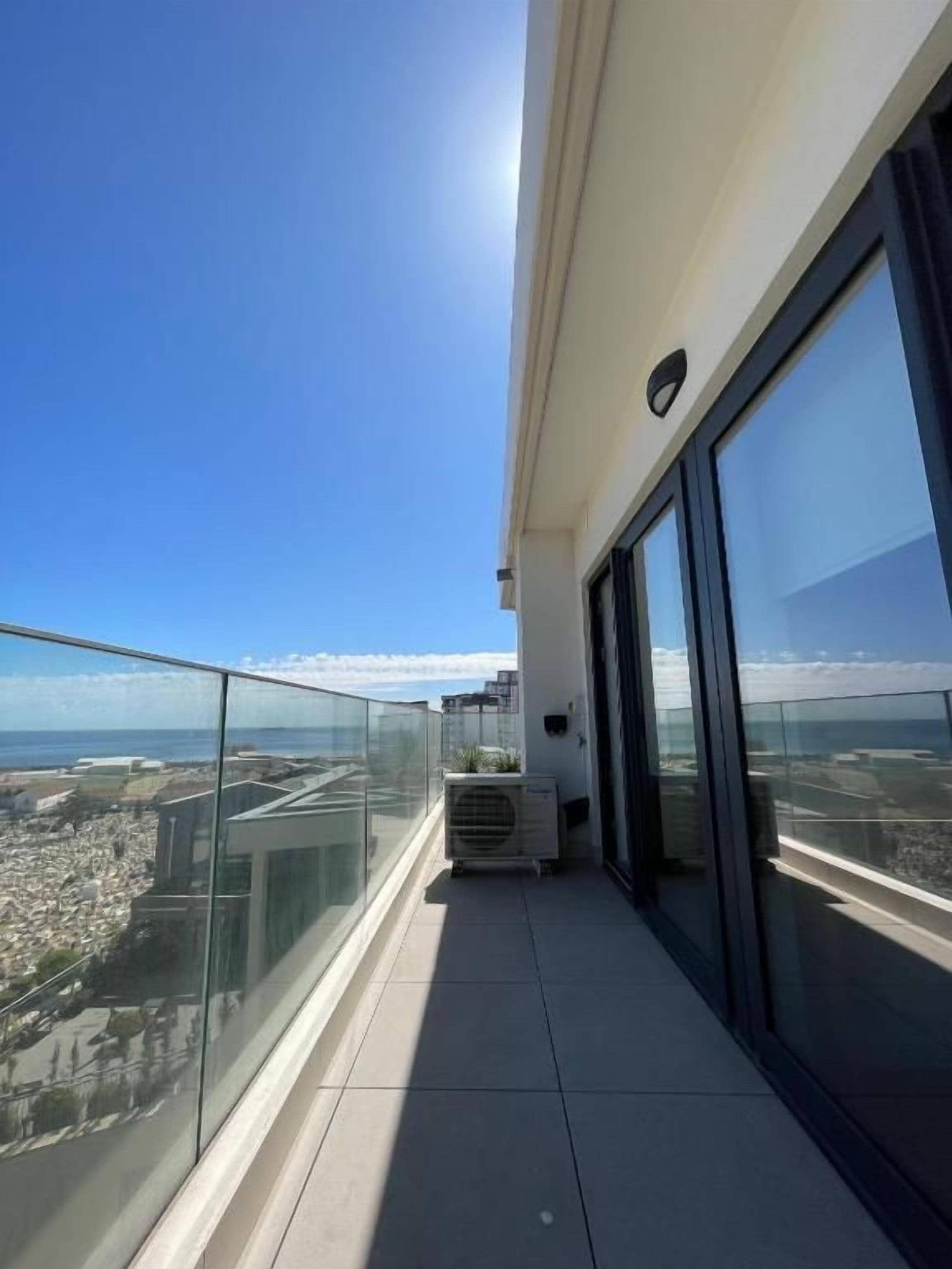 A balcony with a clear view of the cityscape and ocean.