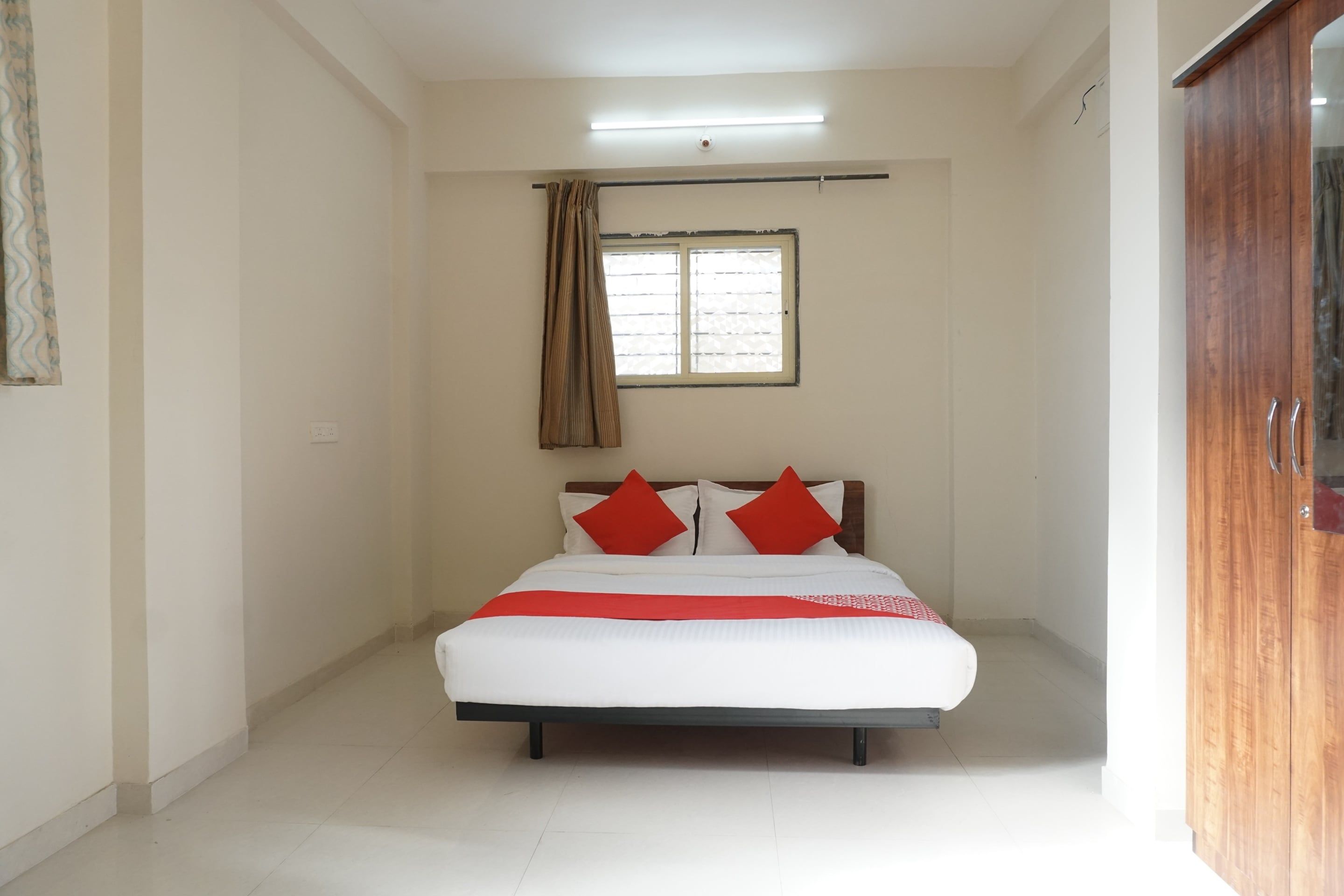 Un dormitorio con cama, ventana con persianas, cortina y armario de madera.